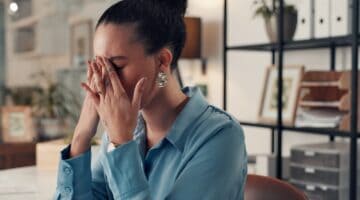 A woman sitting at a desk and looking stressed.