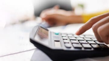 A person using a calculator while reviewing paperwork.