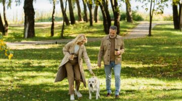 A couple and a dog walking in a park.