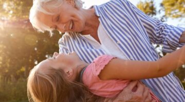 A grandmother playing with her granddaughter outside.