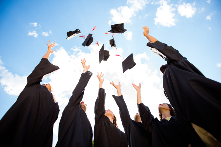 A group of graduates throwing their caps.