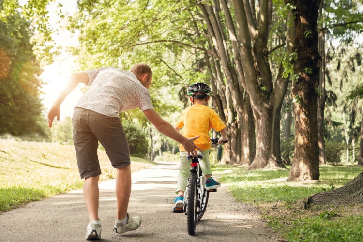 A father teaching a child to ride a bike.