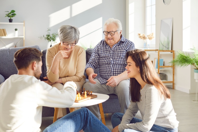 Parents with grown-up children playing chess together.