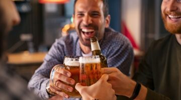 A group of friends clinking beer glasses in a pub.