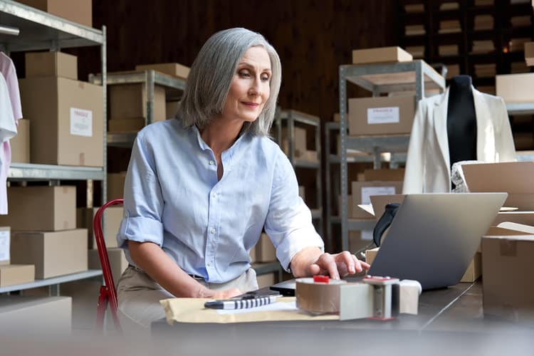 A woman working on a laptop in a warehouse.