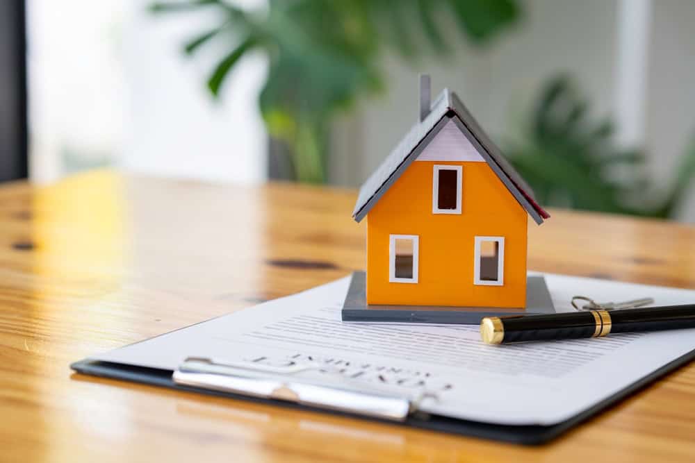 A model of a house sitting on some paperwork.