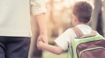 A father and son holding hands as they walk through a park