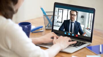 A woman video conferencing on a laptop with a man.
