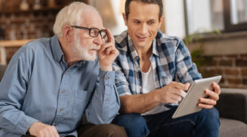 Young man showing his elderly father something on a tablet