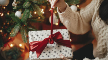 A woman unwrapping a Christmas gift.