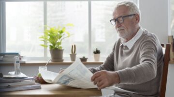 A man reading a newsletter at home.