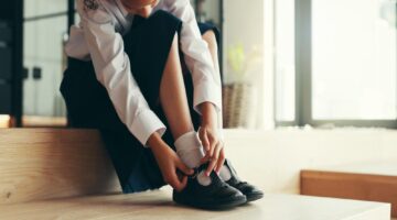 A girl putting on school shoes.