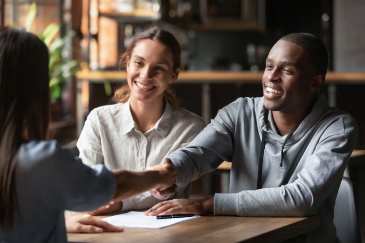 An estate agent shaking hands with a young couple.